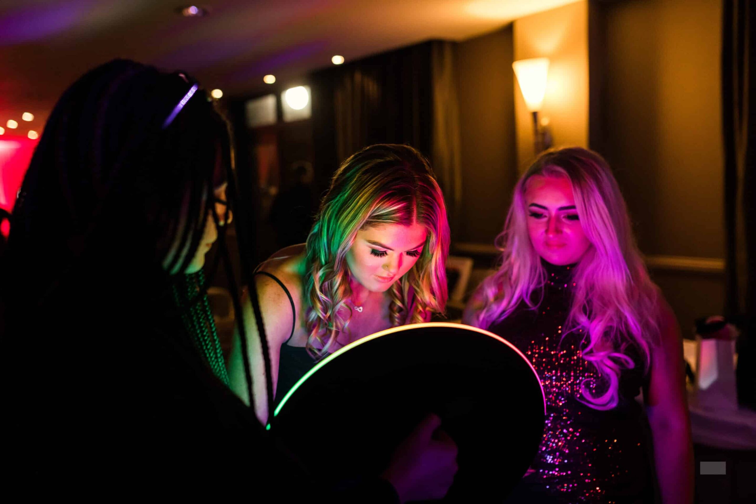 Two women viewing their photos on a photo booth screen in a neon-lit room