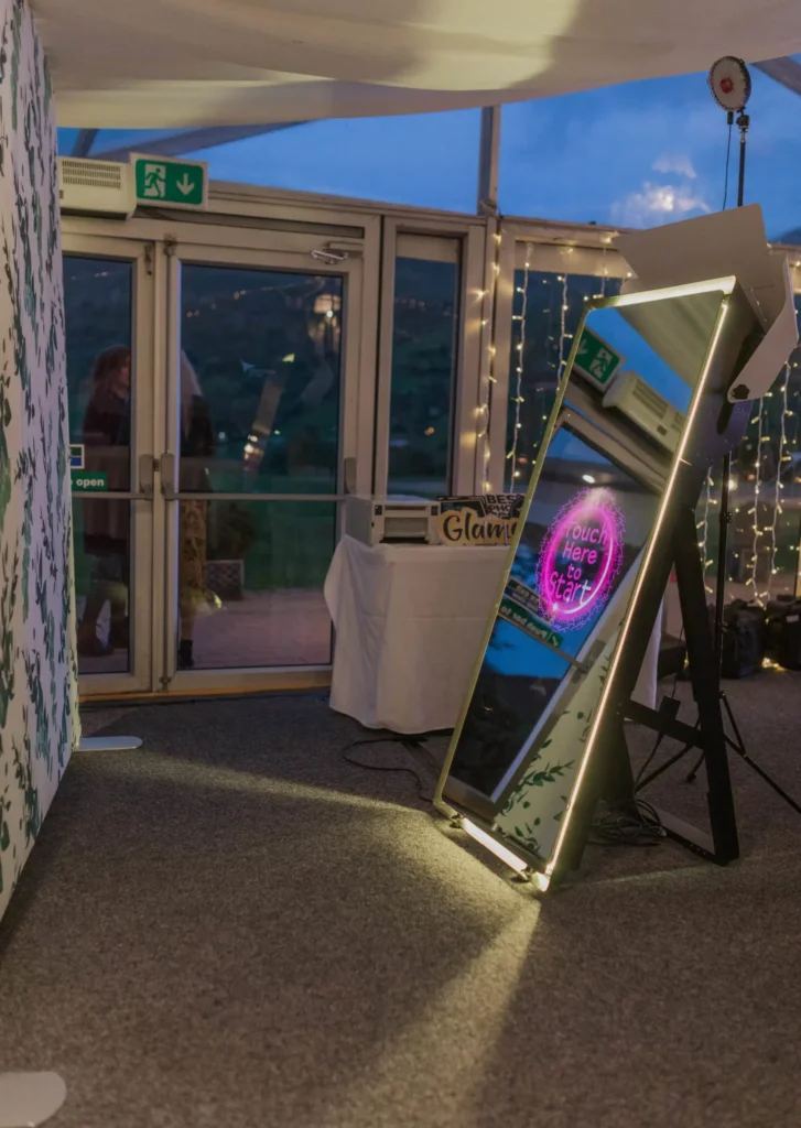 Magic mirror photo booth set up in a venue beside glass doors