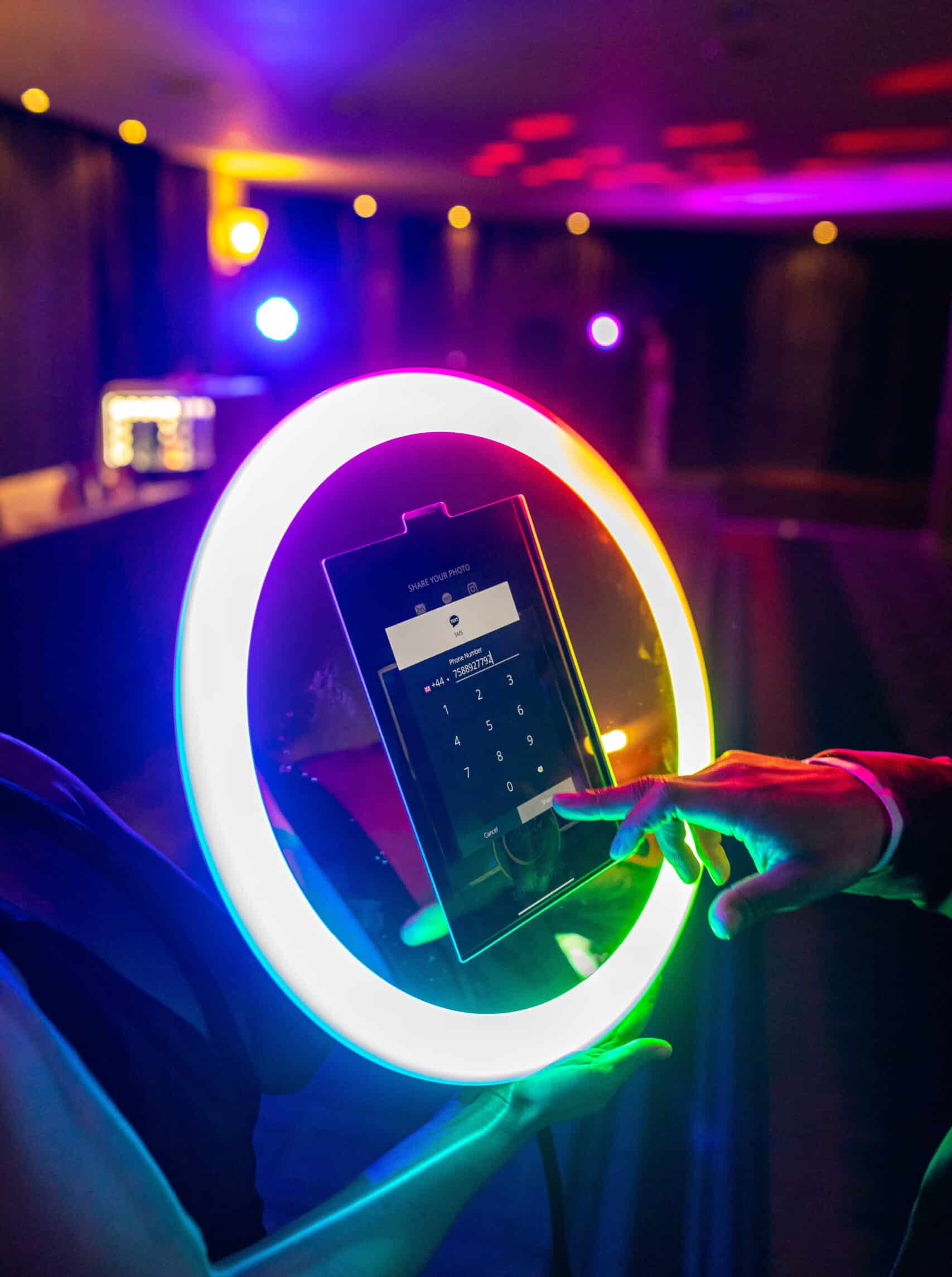 Ring light selfie booth glowing under colorful party lights