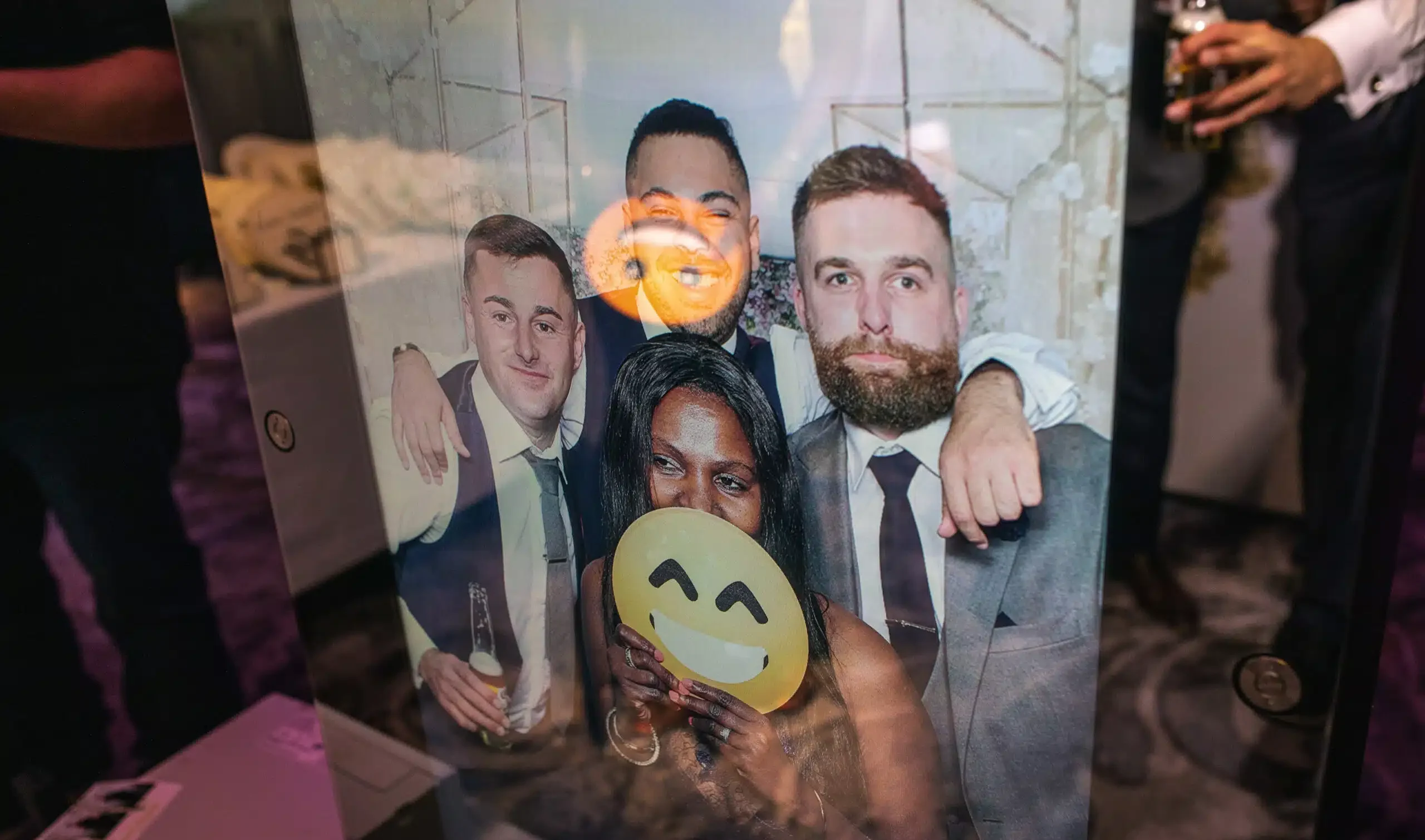 Two men posing with emoji props at a photo booth