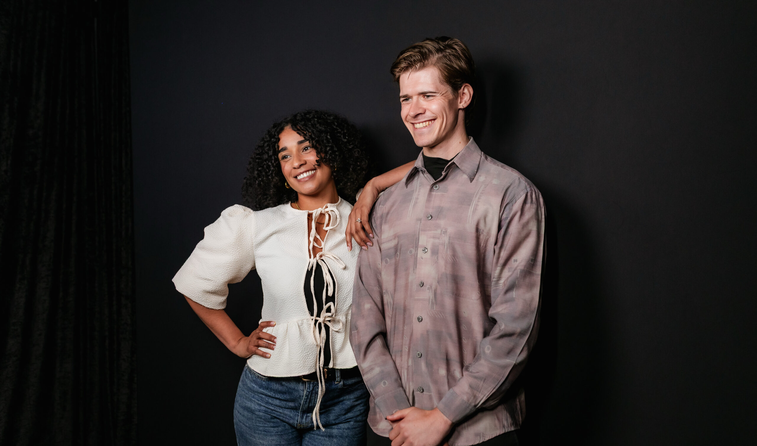 Man and woman posing together against a black photo booth backdrop