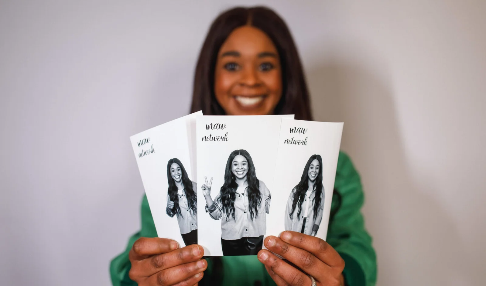 Smiling woman holding a fan of black-and-white photo booth prints