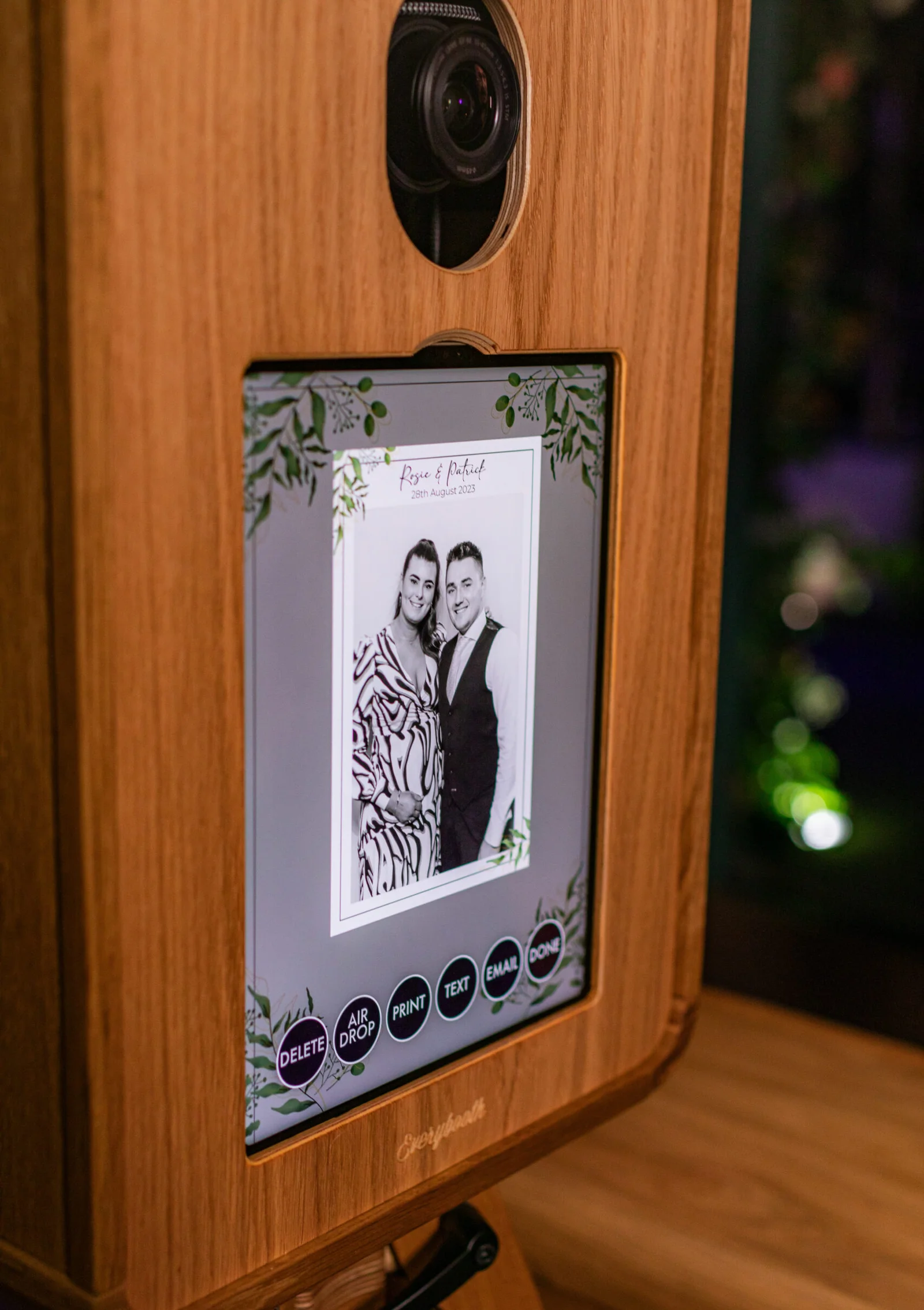 Wooden photo booth kiosk screen displaying a couple's black-and-white photo