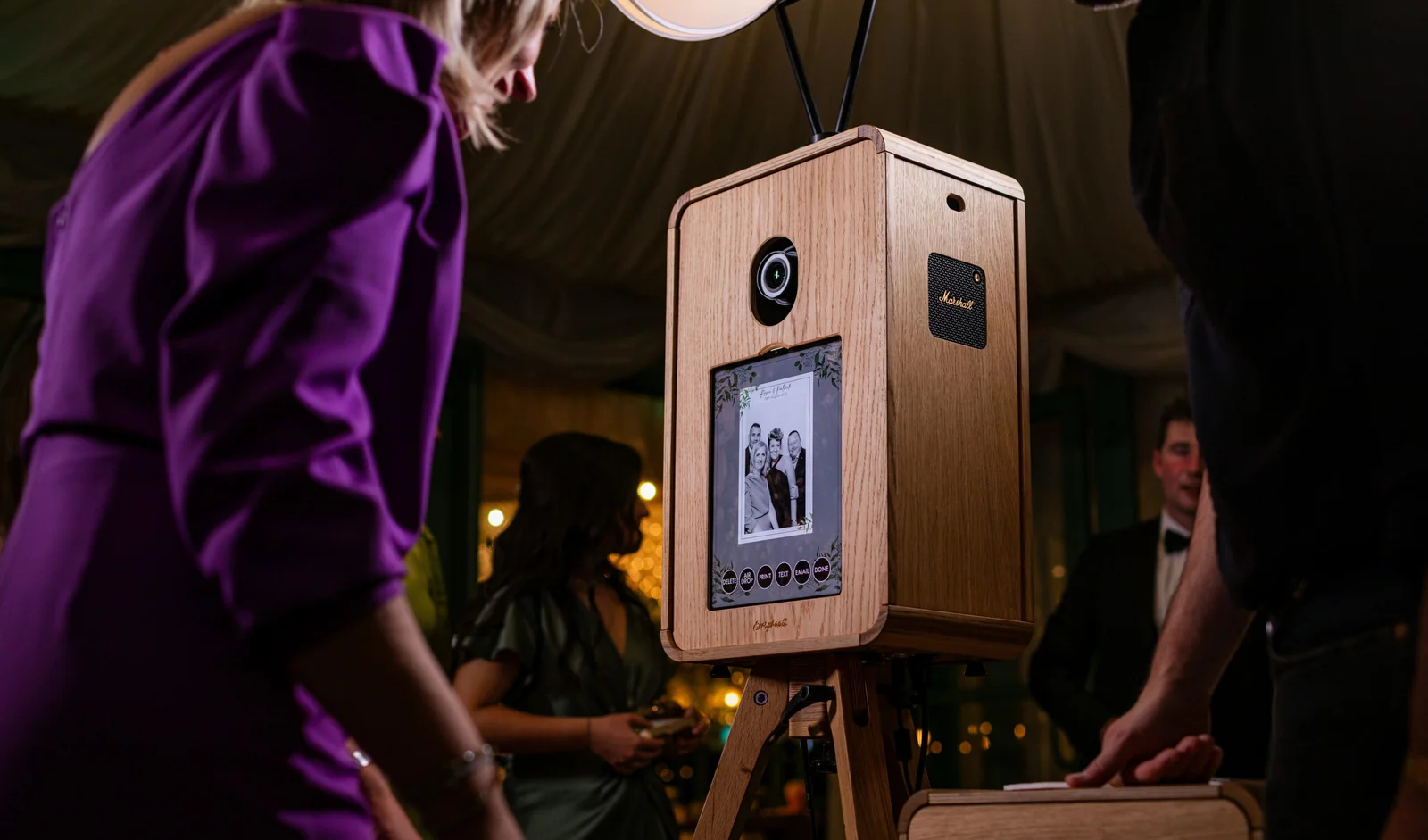 Wooden photo booth kiosk with a touchscreen at an evening event