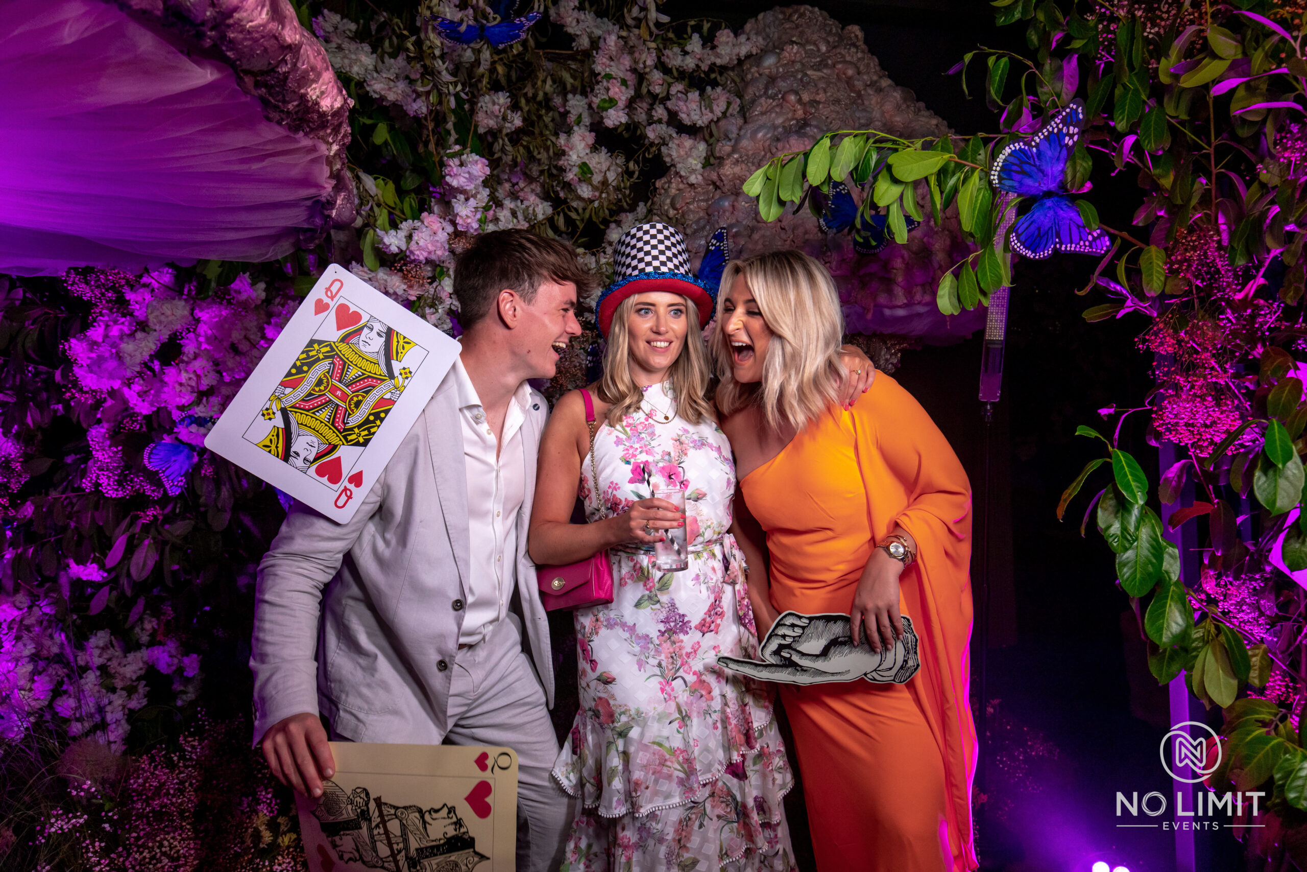Party guests posing for photos on the Everybooth, in front of a flower backdrop and using props