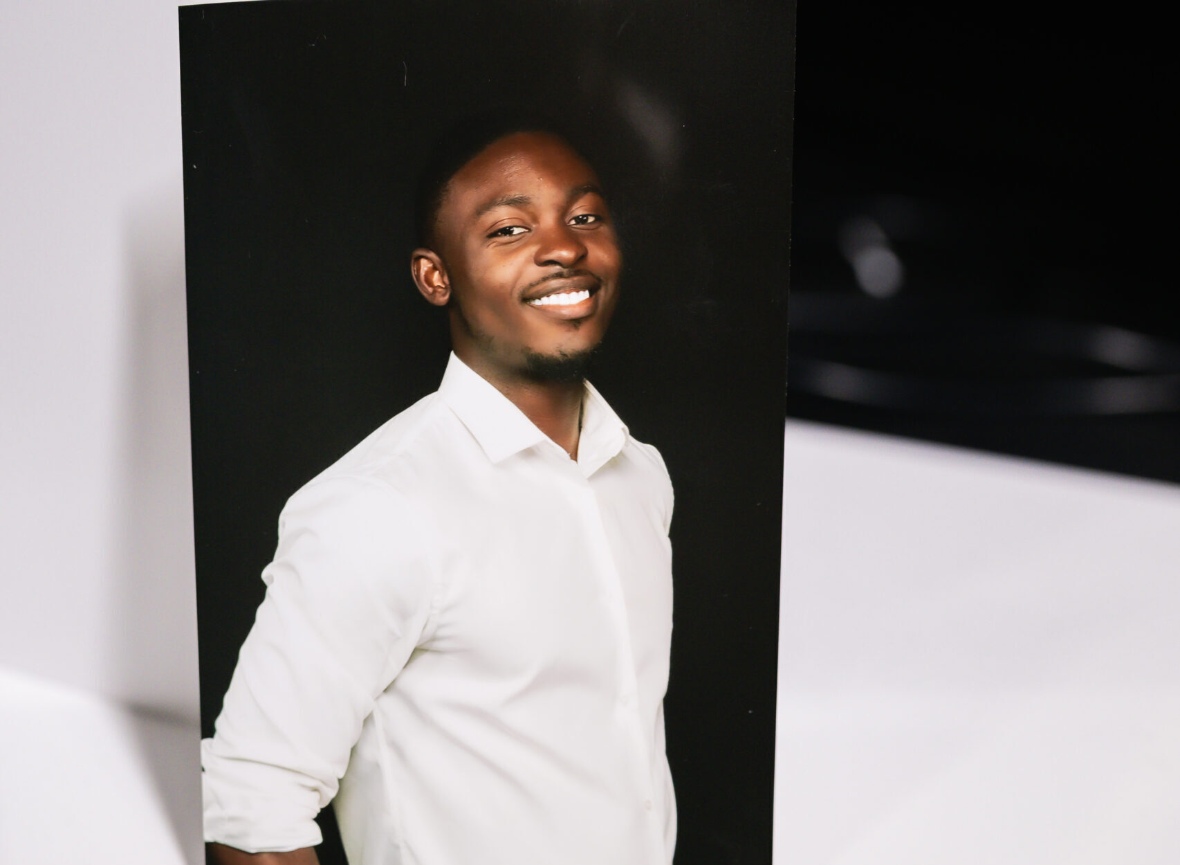 Smiling man in a white shirt posing in a white photo booth