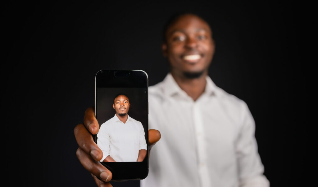 Man holding up a phone showing his photo booth picture