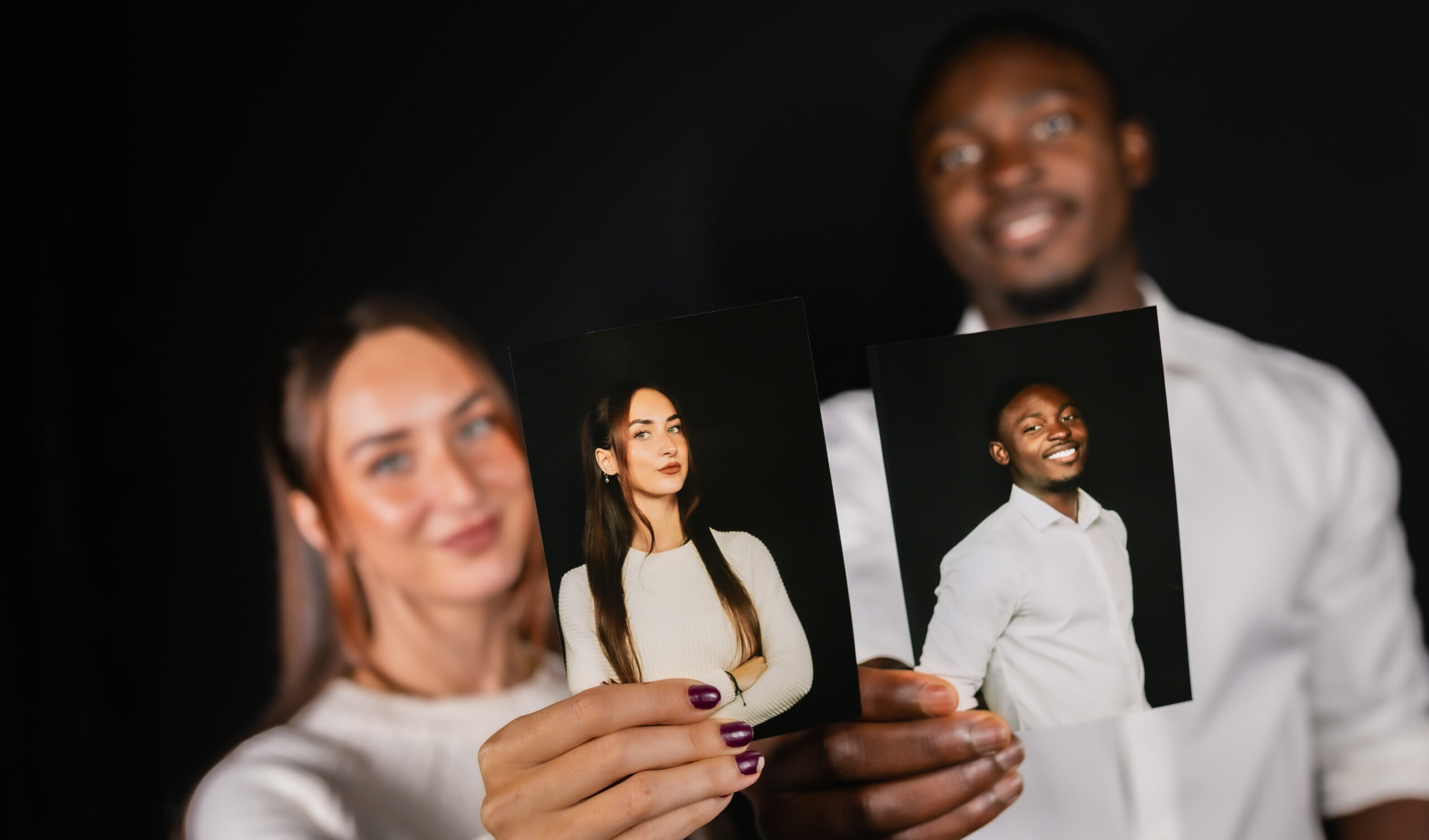 Guests smiling as they hold up their printed photo booth pictures