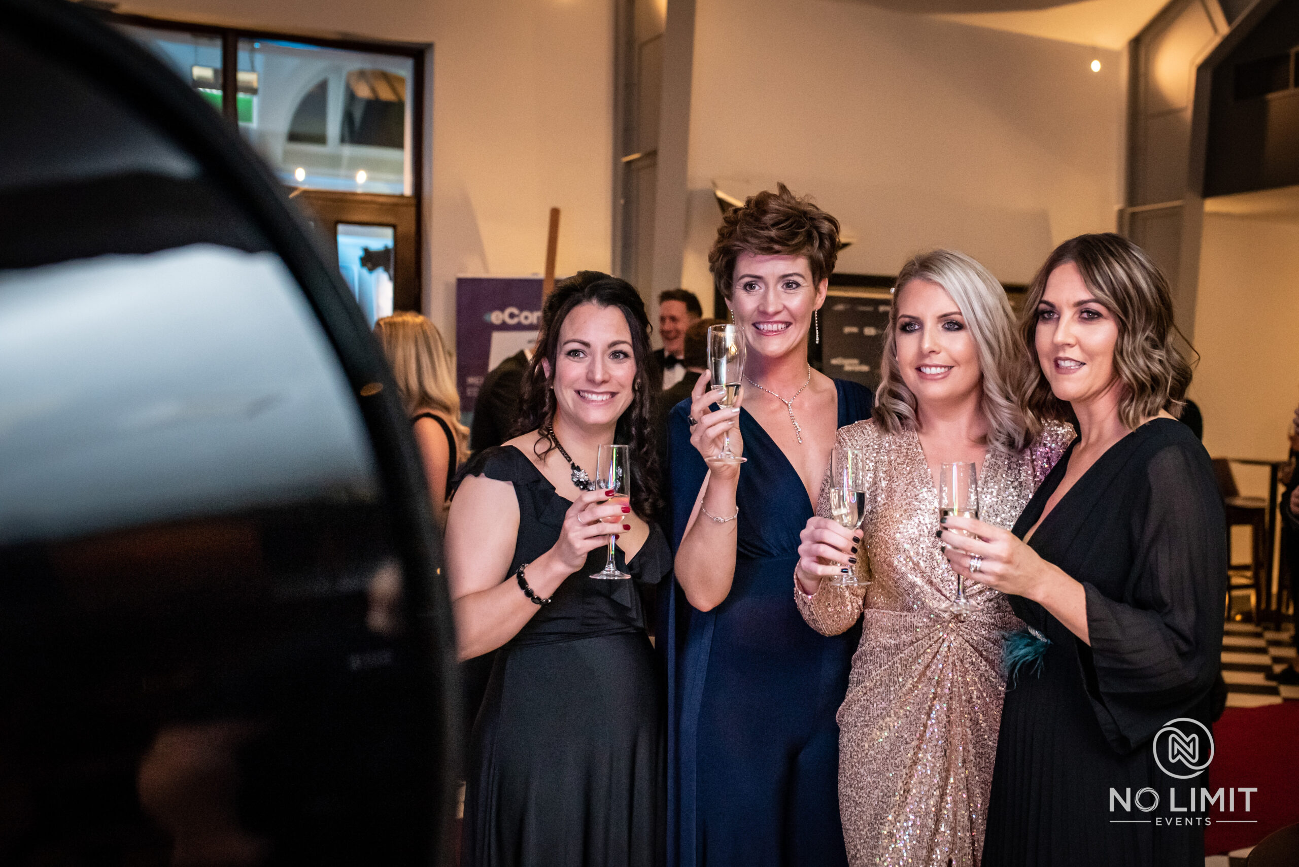Guests at black tie event posing to have their photos taken, wearing pretty dresses and drinking champagne