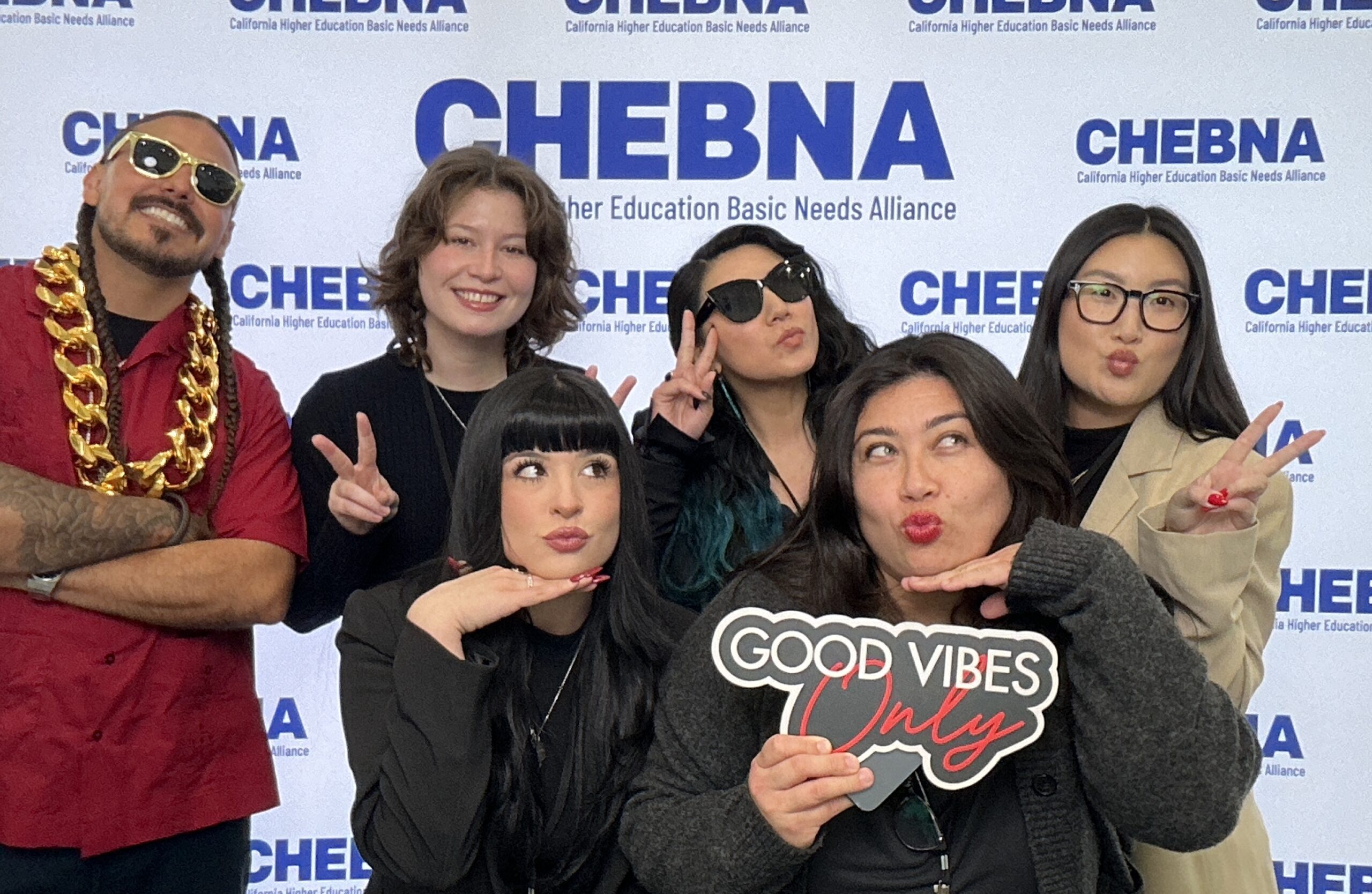 Guests posing with a "Good Vibes" sign in front of a CHEBNA event backdrop
