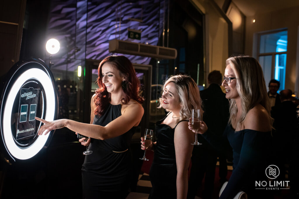 Woman viewing photos on a booth screen with friends at a nighttime event