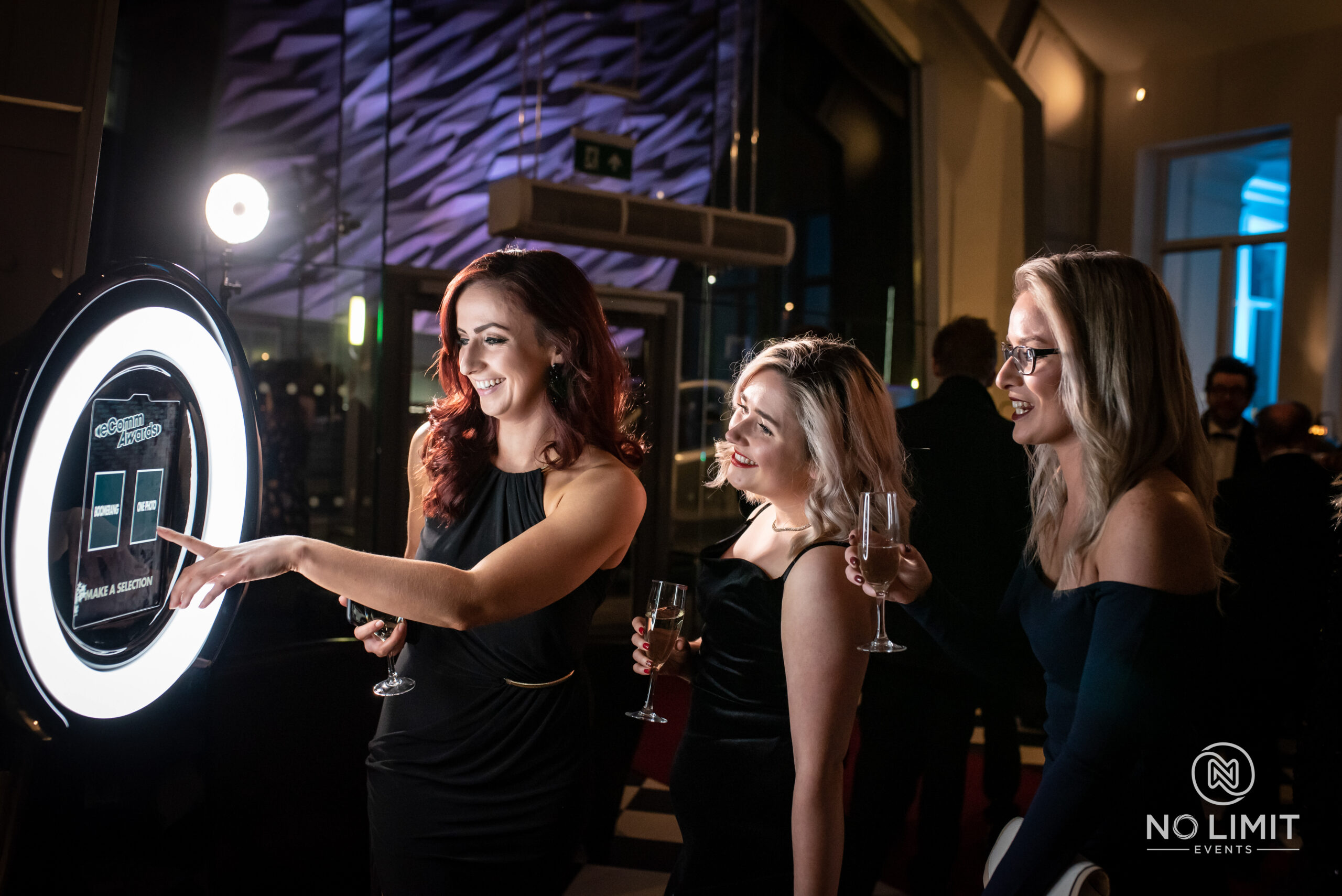 Woman viewing photos on a booth screen with friends at a nighttime event