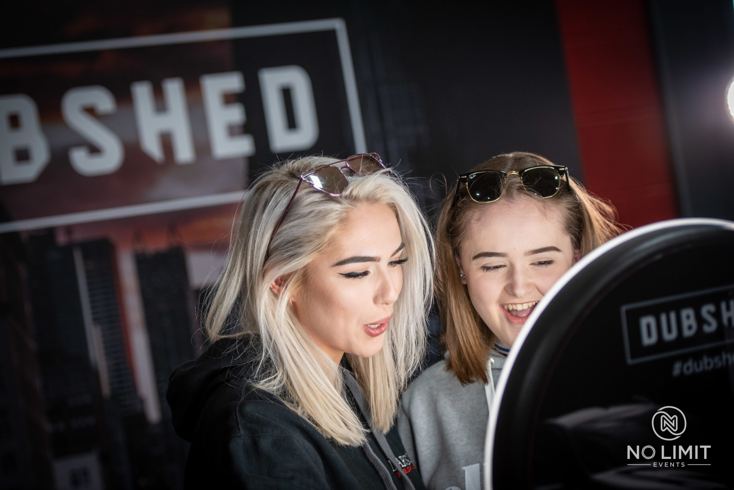 Two young women checking their photos on a ring light booth screen