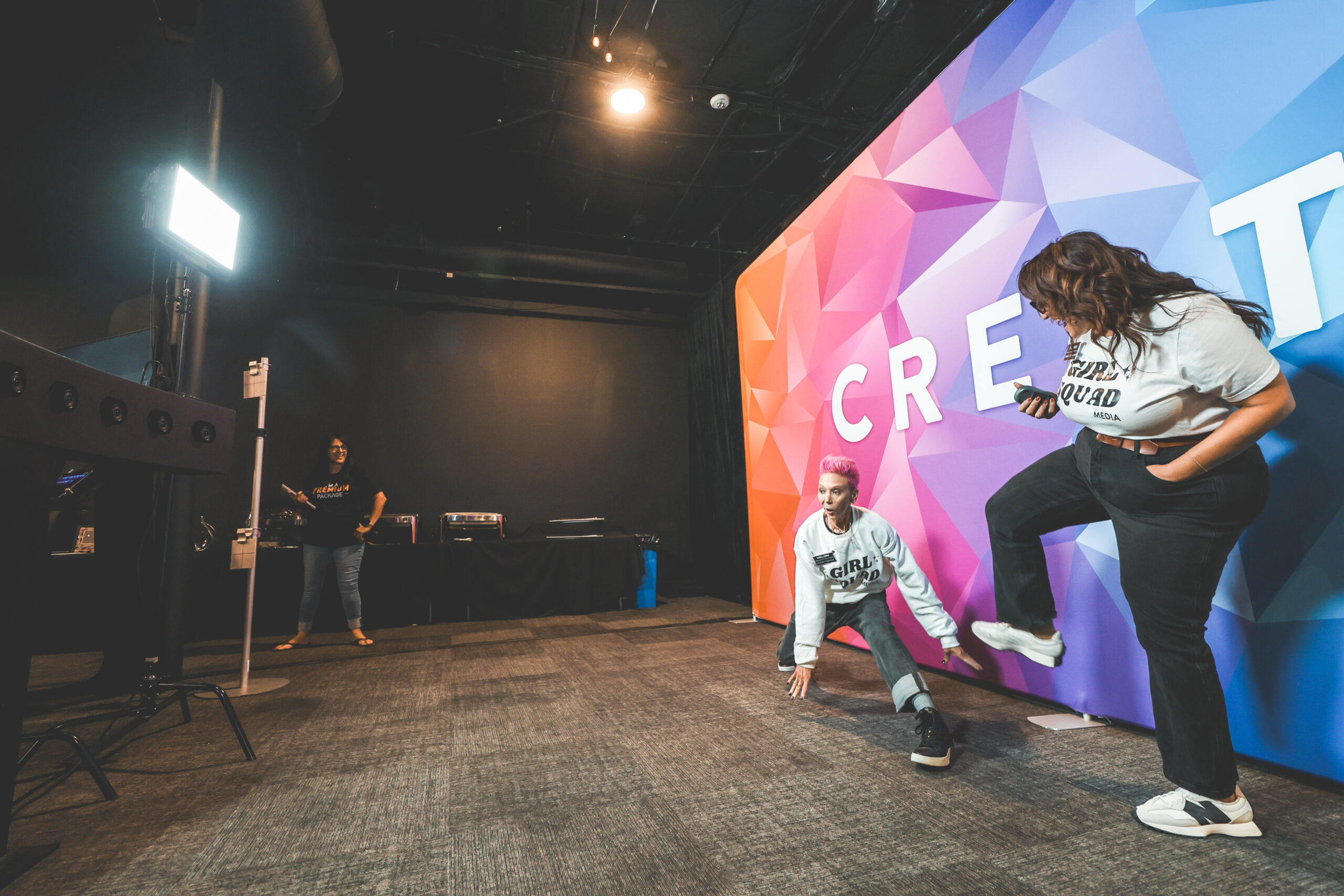 Vertical bullet-time camera array rig with mounted lighting filming two guests dancing in front of a colorful CREATE branded backdrop